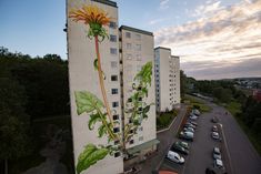 an aerial view of a large building with flowers painted on it's side and cars parked in the parking lot