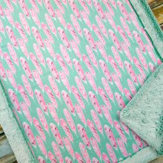 a green and pink blanket sitting on top of a wooden bench