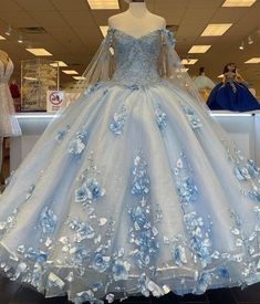 Make your quinceanera celebration magical with this Sky Blue 3D Applique Off-Shoulder Ball Gown Quinceanera Dress. The classic ball gown is crafted from delicate tulle, creating a voluminous and graceful look fit for a princess. The off-the-shoulder neckline enhances the romantic allure, framing your shoulders beautifully. The intricate 3D appliques adorn the gown, adding texture and artistry to its ethereal design. The corset back ensures a flawless fit, giving you both support and style as you Light Blue Long Dress, Light Blue Quinceanera Dresses, Baby Blue Quinceanera, Xv Dresses, Quinceanera Themes Dresses, Blue Long Dress, Off Shoulder Ball Gown, Ball Gown Prom Dresses, 3d Applique