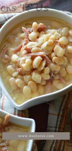 two bowls filled with beans and ham on top of a plaid table cloth next to bread