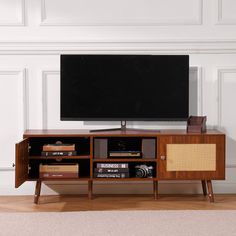 a flat screen tv sitting on top of a wooden entertainment center next to a wall