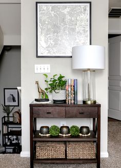 a living room with a table, lamp and pictures on the wall