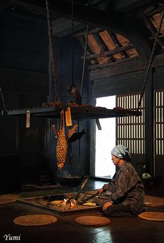 a woman sitting on the floor in front of an open door with birds hanging from it