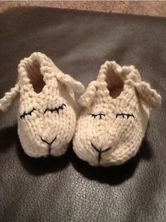 two crocheted sheep slippers sitting on top of a leather couch