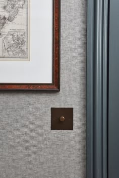 a framed map is hanging on the wall next to a door with a brown latch