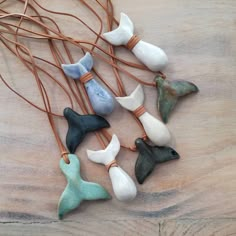 small ceramic birds are hanging from a wire on a wooden table with brown cords and leather cord