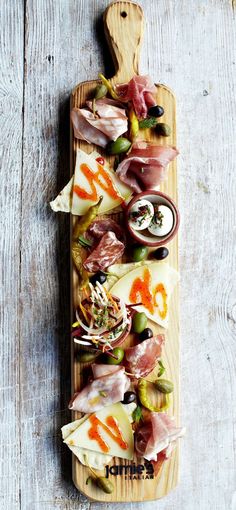 an appetizer with meats and vegetables on a wooden platter, ready to be served