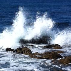 a person riding a surfboard on top of a wave in the ocean next to rocks