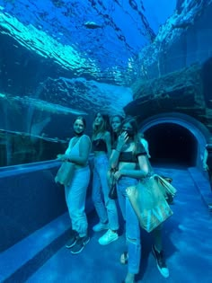 three women standing in front of an underwater tunnel