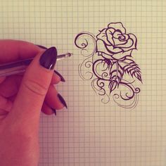 a hand holding a pen and drawing a rose