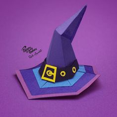 an origami wizard hat on top of a piece of purple paper with yellow accents