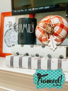 an orange and white plaid ball sitting on top of a stack of books next to a coffee mug