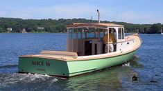 a green and white boat on water with trees in the background