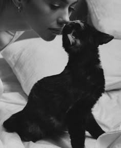 a woman laying in bed next to a black cat