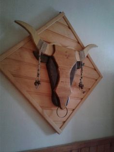 a wooden wall mounted with two horns and beads