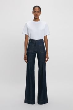 A signature silhouette in the brand’s denim archive, the high waist and flared leg of the seventies-inspired Alina Jean is cut to flatter every figure. Inspired by Victoria’s own vintage denim collection, it is presented exclusively for AW24 in a indigo Rinse raw indigo denim for a bohemian sensibility. Tobacco topstitching and a red Victoria Beckham embroidered monogram on the right front pocket add polish, while a branded leather patch at the waistband completes the look. Styled with the ... Patch Pocket Jeans Outfit, Dark Denim Jeans Outfit, Patch Pocket Jeans, Victoria Beckham Jeans, Denim Jeans Outfit, Denim Street Style, Victoria Beckham Style, High Waisted Jean, Vintage Denim Jeans