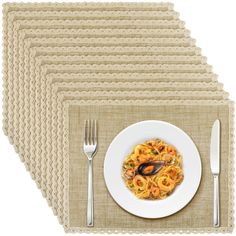 a white plate topped with pasta next to silverware and fork on top of a place mat