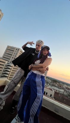 two people standing next to each other on top of a building