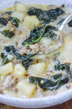 a bowl of soup with spinach, potatoes and meat