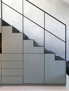 the stairs are painted white and have black railings on each side, along with gray cabinets