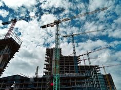 several cranes are in front of a building under construction