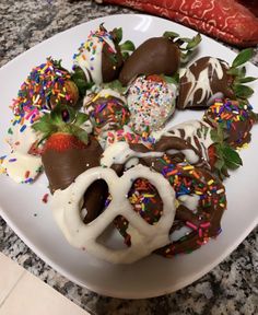 a white plate topped with lots of chocolate covered strawberries and pretzel rings