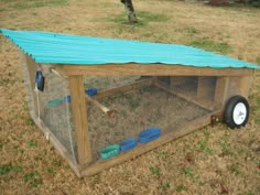 a chicken coop with a blue tarp on top and wheels attached to the roof