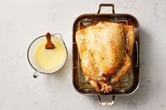 a roasting pan filled with chicken next to a glass of milk and a spoon