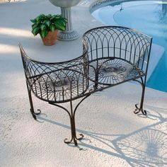 a wrought iron bench next to a swimming pool