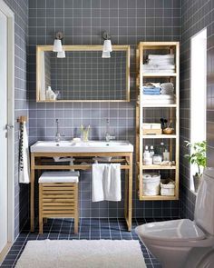 a bathroom with gray tiles and white towels on the shelf above the sink is an open shelving unit