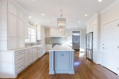 a large kitchen with white cabinets and wood floors