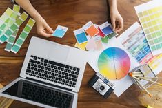 two people working at a table with different color samples and paint swatches on it