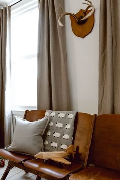 a brown leather chair sitting in front of a window next to a wall mounted deer head