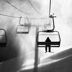 a person standing under a ski lift in black and white with shadows on the ground