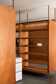 an open bookcase in a room with white drawers and wooden shelves on the wall