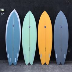 three surfboards are lined up against a wall