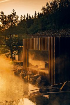 steam rises from the water in front of a wooden structure