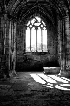 the sunlight is shining in an old building with stone columns and arched glass windows on each side