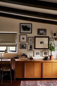 a living room with pictures on the wall and a table in front of it,