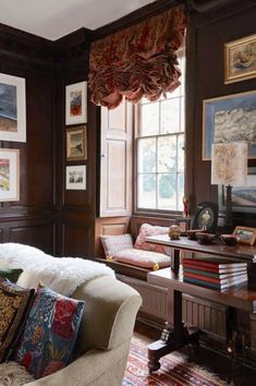 a living room filled with lots of furniture and pictures on the wall above it's windows