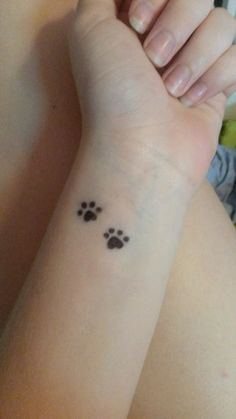 a woman's arm with a small paw tattoo on the left side of her wrist