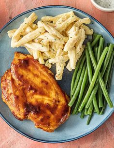 a blue plate topped with chicken, green beans and pasta