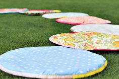 several circular cushions are lined up on the grass, with polka dots and flowers all over them