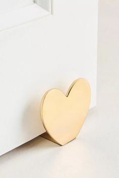 a gold heart shaped object sitting on top of a white surface next to a door