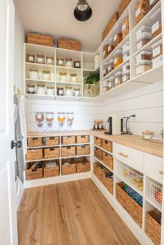 an organized pantry with lots of baskets and food on the shelves, along with wooden flooring