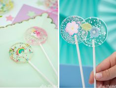 a hand holding three lollipops on top of a table next to a cake