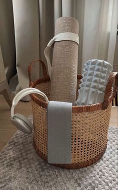 a wicker basket with two rolls of toilet paper and headphones on the floor