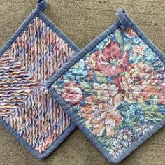 two pieces of cloth with flowers on them sitting next to each other in the sand