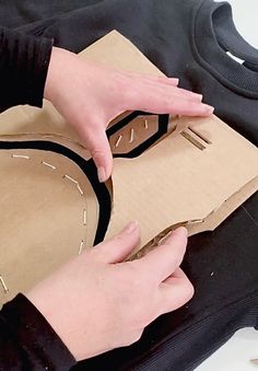 someone is cutting out some paper on top of a piece of cardboard with scissors and tape