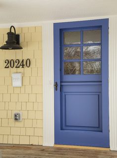 a blue front door with a brick wall and light fixture on the side of it